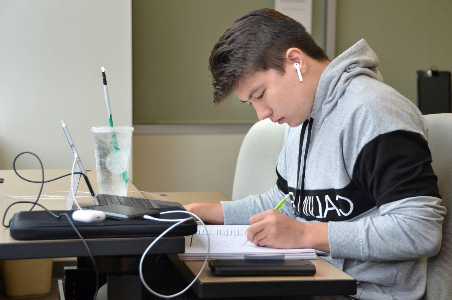 Student studying at desk with pencil, notebook, and computer